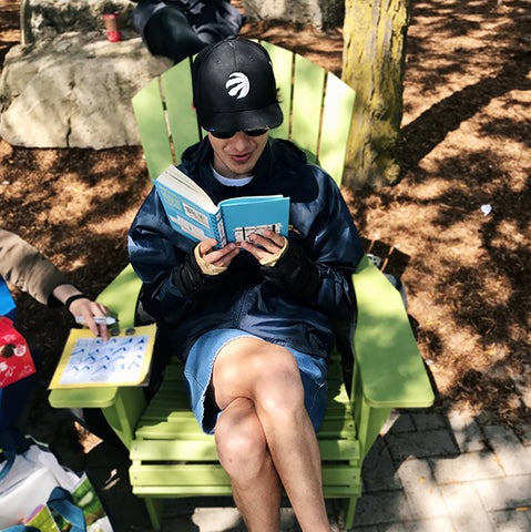 Young adult reading book outside on an Adirondack chair