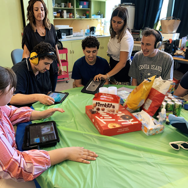 Adults around a table playing on tablets and getting ready to eat